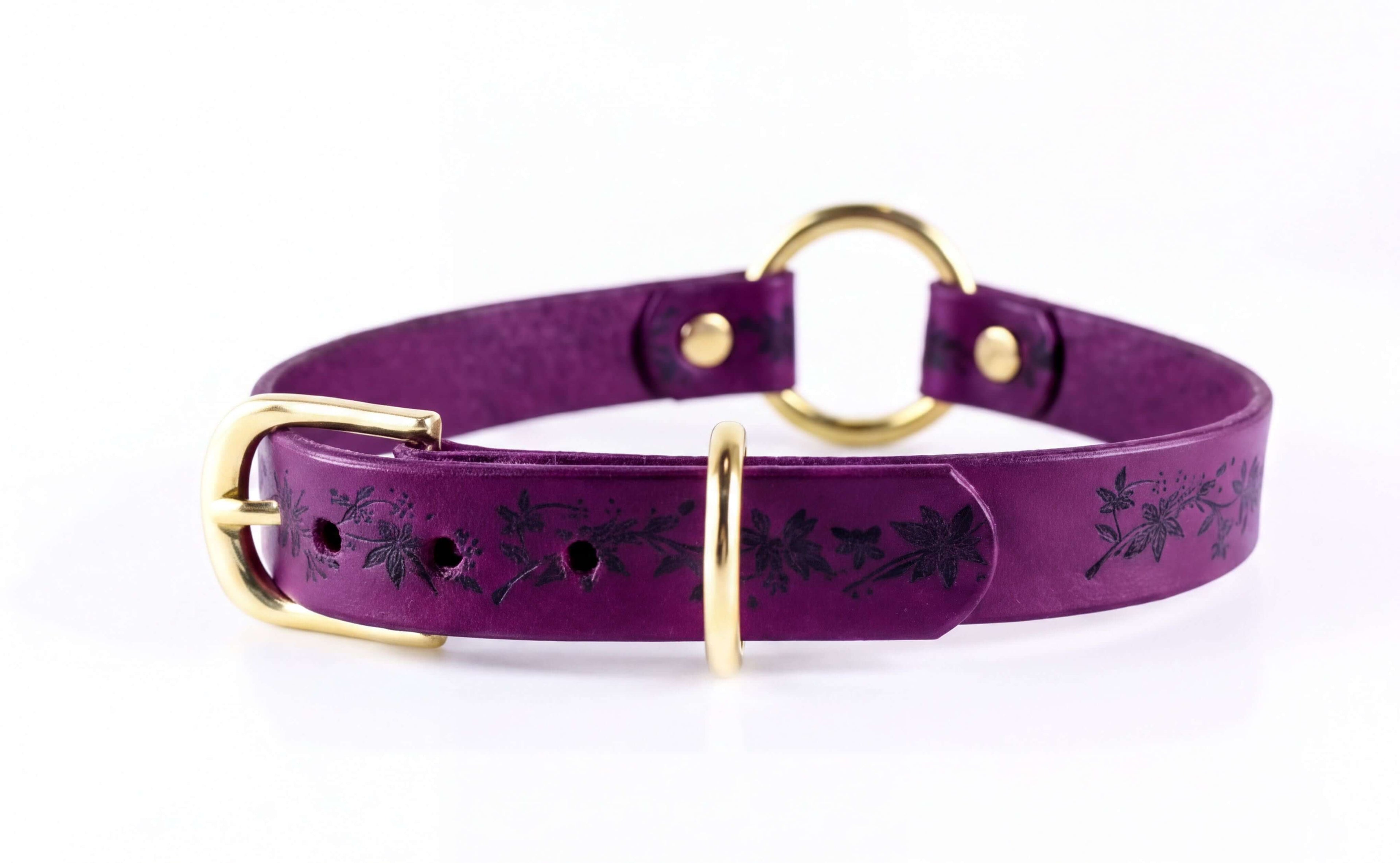 A purple leather choker collar with a gold buckle and a floral pattern on the strap.