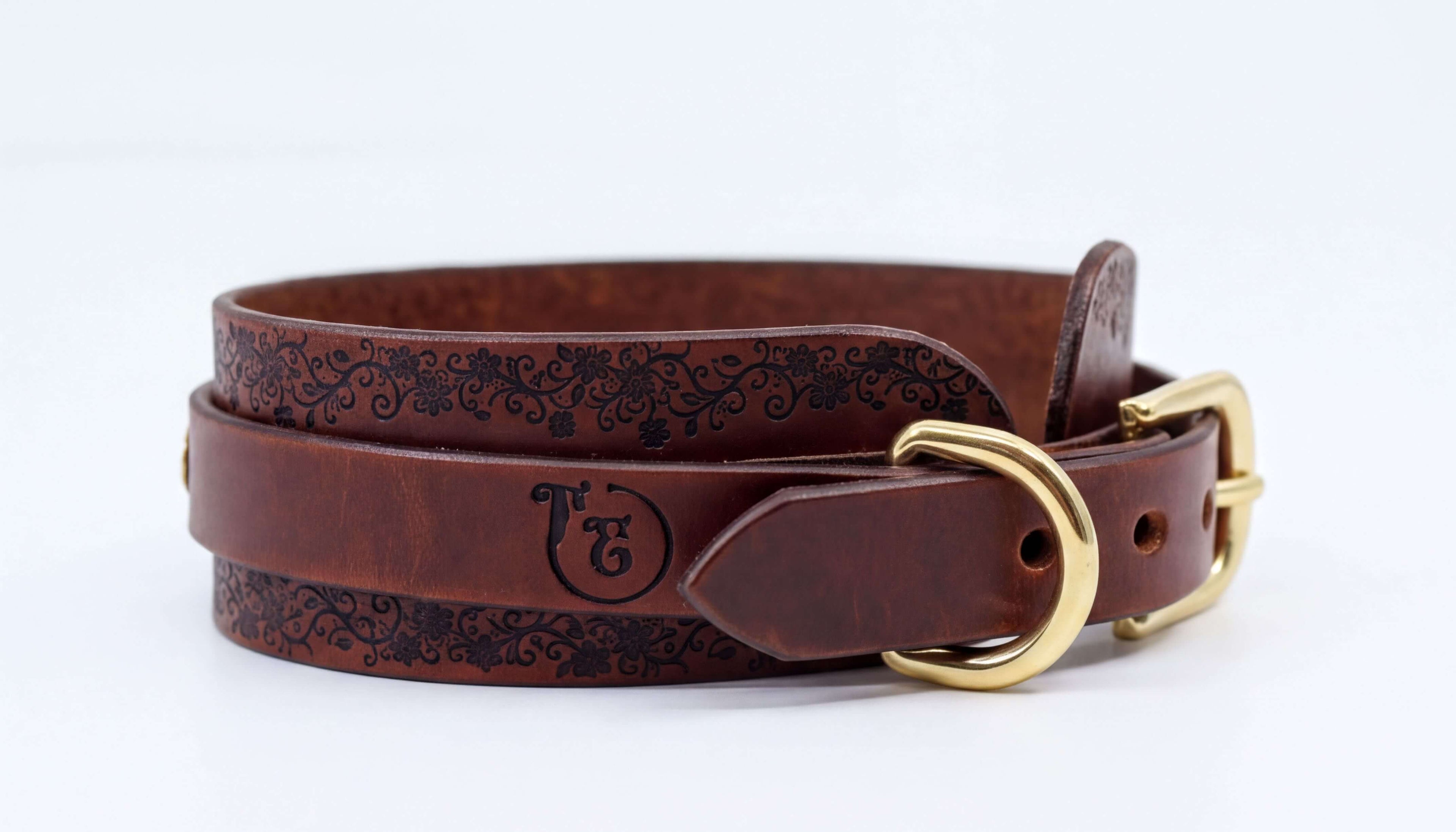 A brown leather belt with a decorative pattern and a gold buckle.