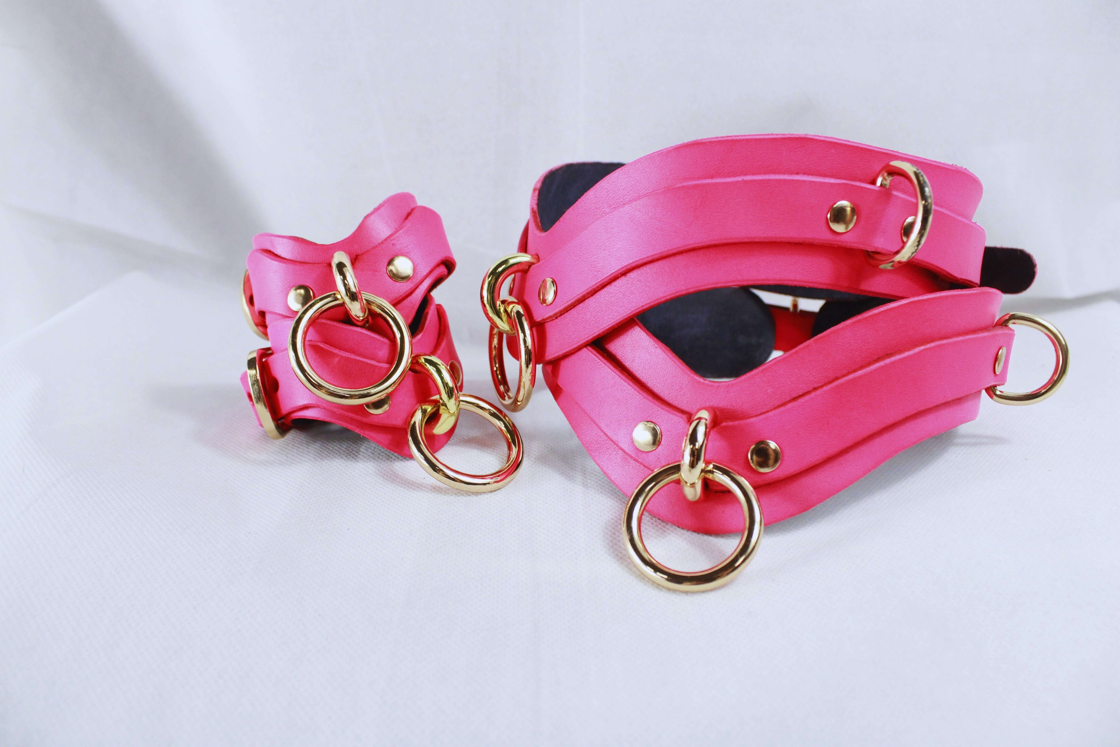 Elegant pink bondage restraint set with gold hardware, featuring a collar and cuffs for BDSM play and submissive experiences.
