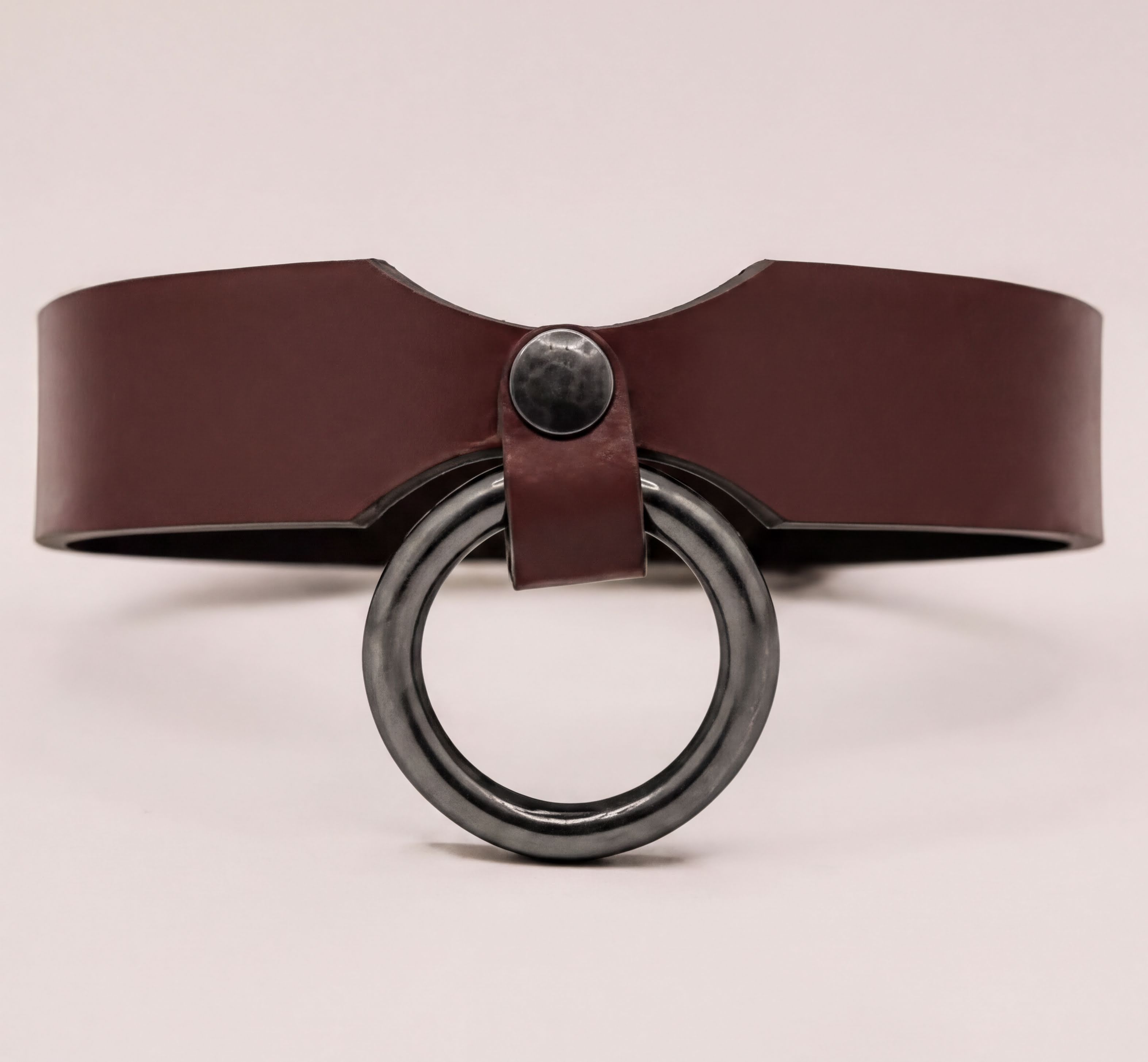 A brown leather choker necklace with a black metal ring on the front.