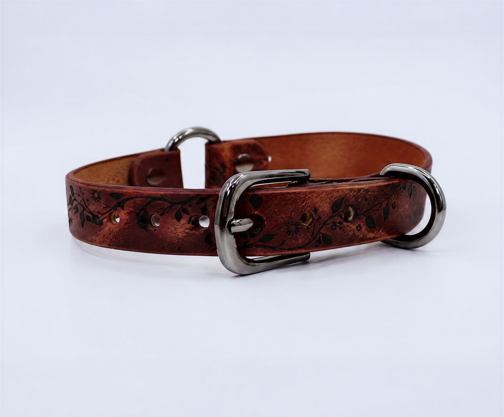 A brown leather dog collar with a metal buckle and decorative pattern on the surface.