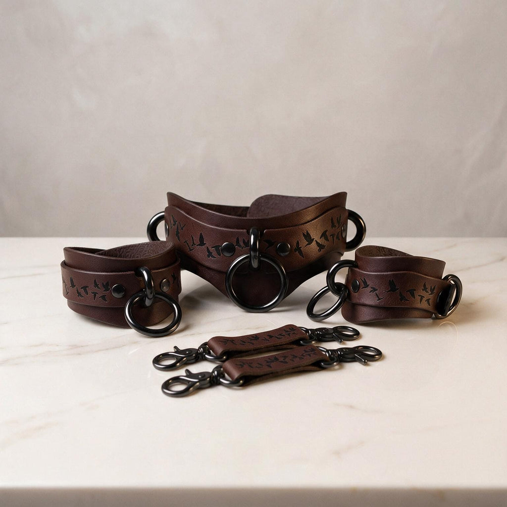 A set of brown leather straps with metal rings and buckles, arranged on a white surface.