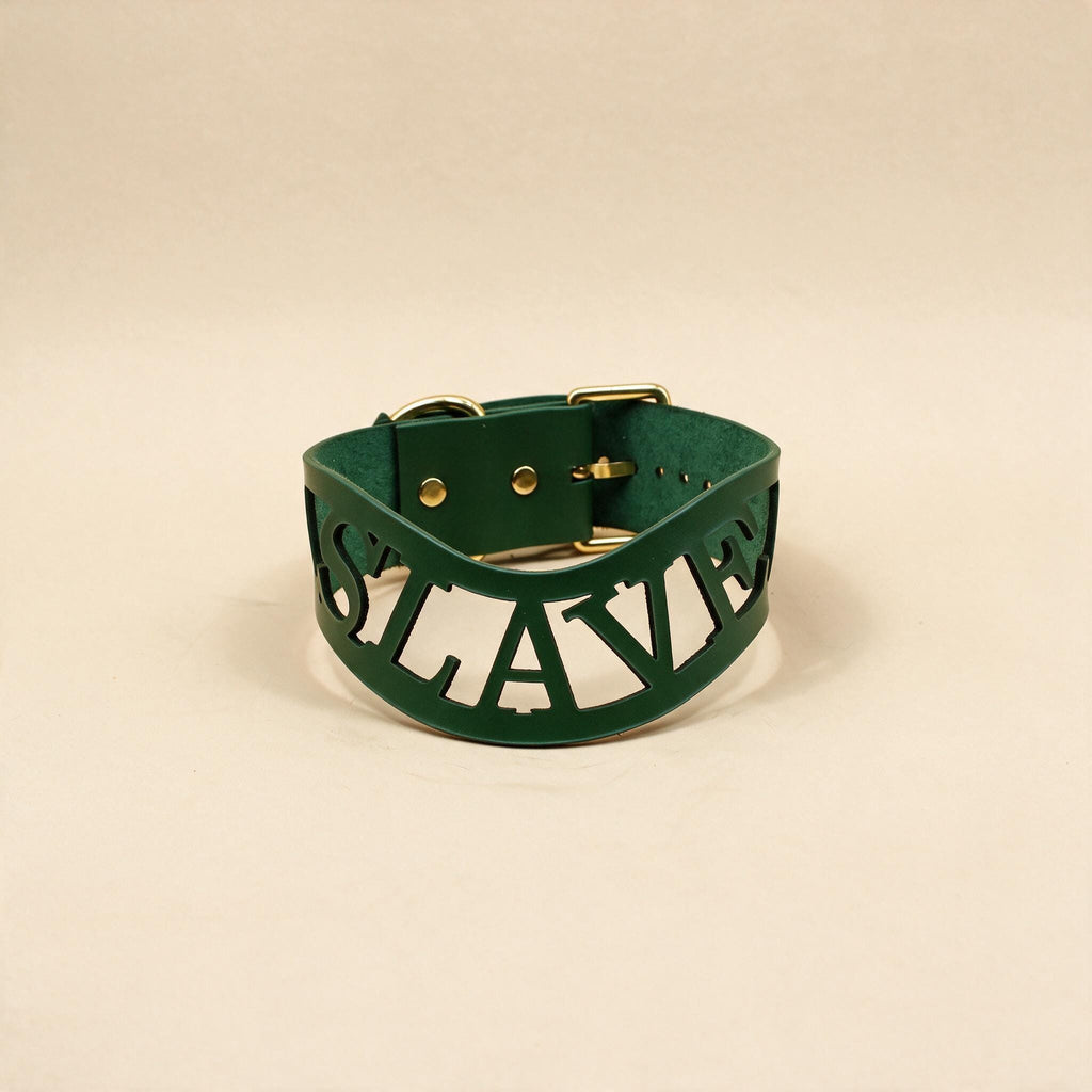 A green leather choker necklace with the word "SLAVERY" printed on it in a bold, capitalized font.