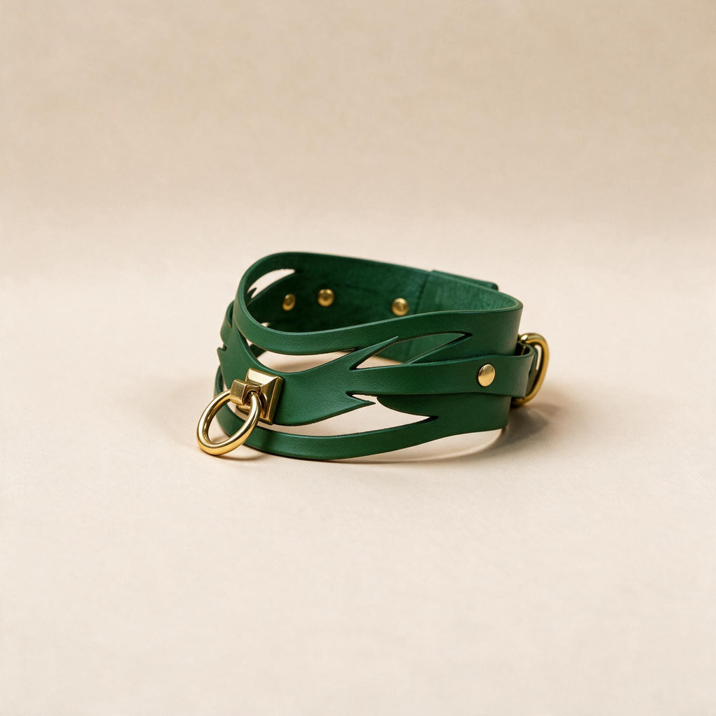 A green leather choker necklace with gold-colored metal rings and buckles.