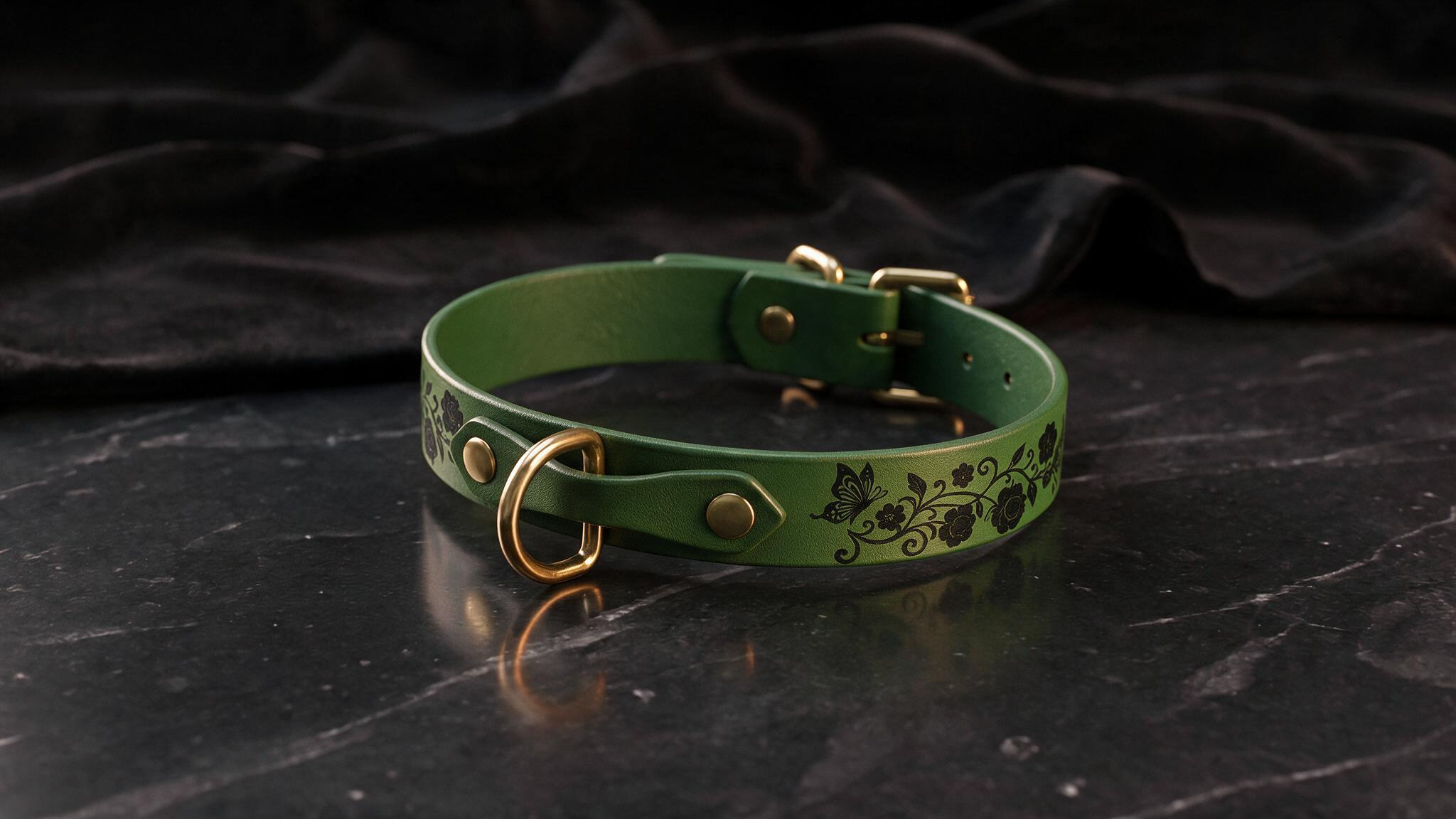 A green leather collar with a floral design and a gold buckle is displayed on a black marble surface.