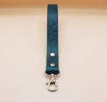 A dark green leather strap with a metal clasp and hook attached to it.