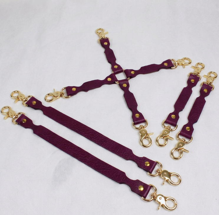A set of purple leather straps with gold-colored metal clasps, arranged in a pattern on a white background.