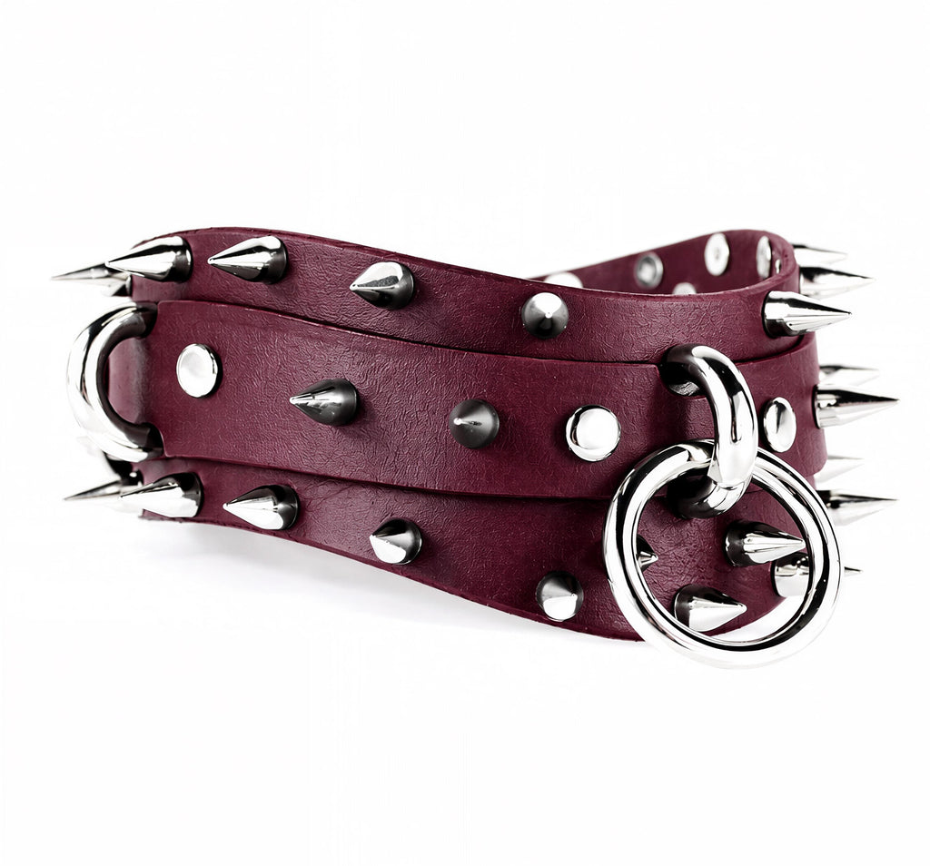 A burgundy leather belt with silver spikes and a metal ring attached to it.