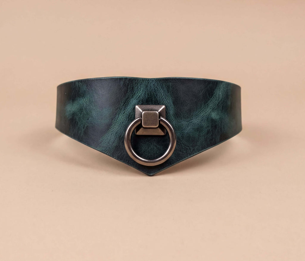 A dark green leather choker necklace with a metal ring and a square-shaped metal piece on the front.