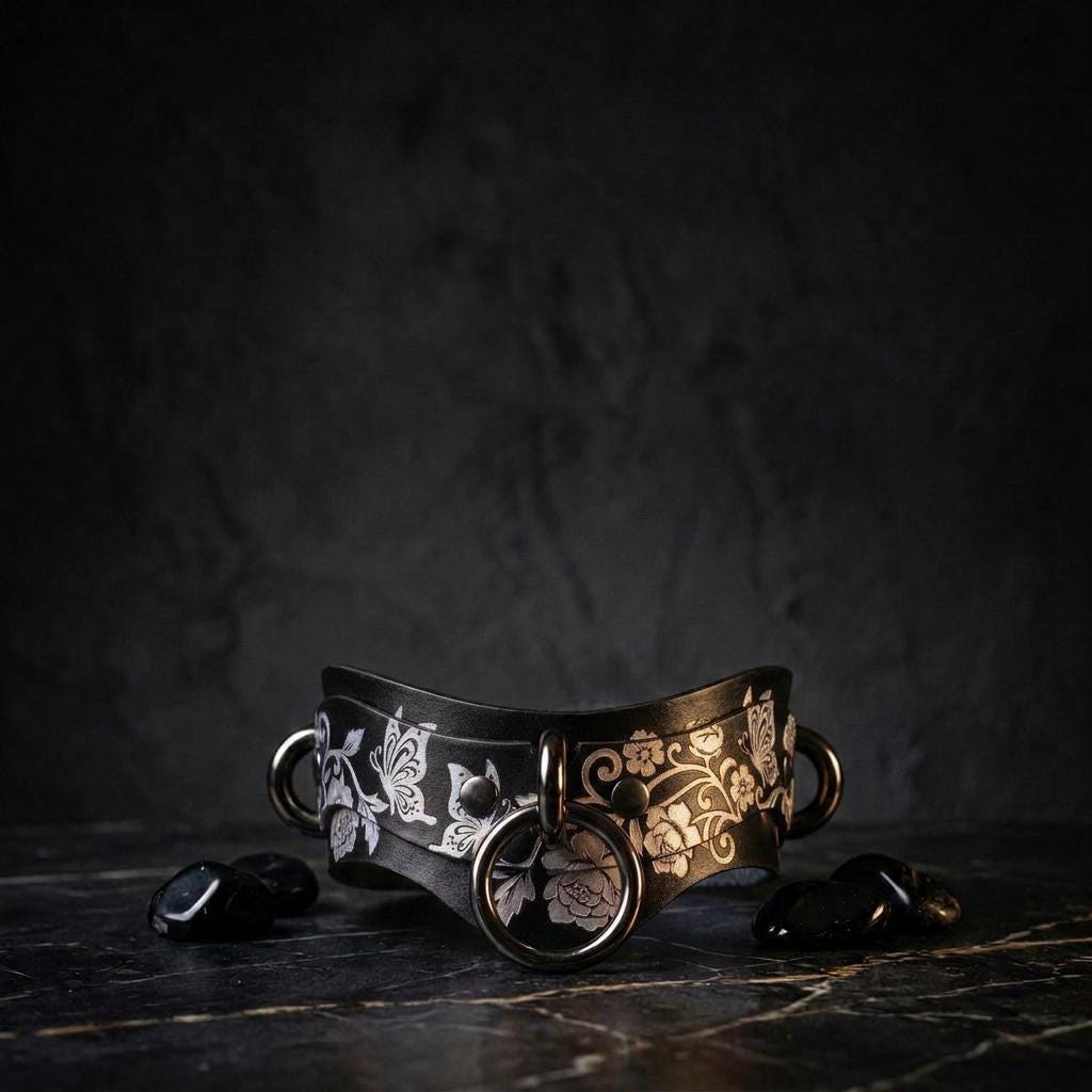 A black and white floral collar with metal rings and stones on a dark surface.