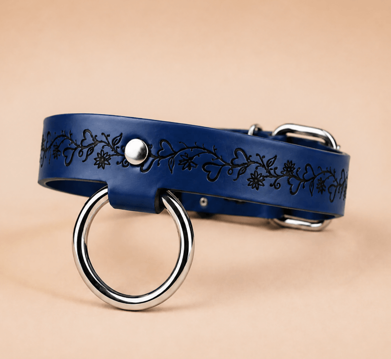 A blue leather collar with a metal ring and floral designs on the band.