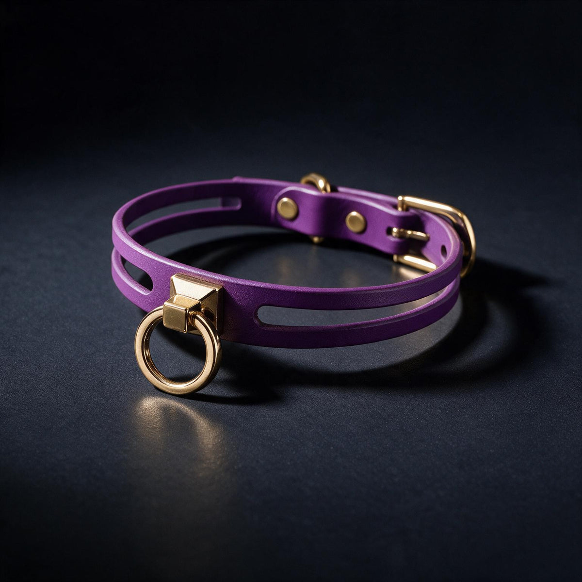A purple leather choker necklace with a gold-colored metal clasp and ring is displayed against a dark background.