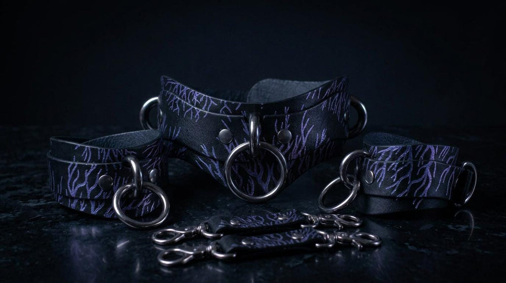A set of dark purple leather choker necklaces with metal rings and buckles, arranged on a dark surface.