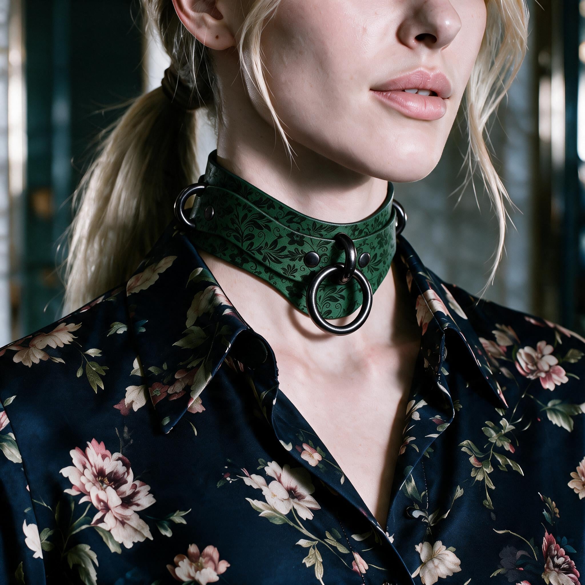A close-up of a woman wearing a green choker necklace with a floral pattern, paired with a dark floral blouse.