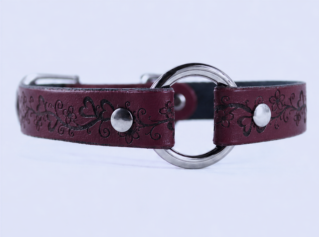 A burgundy leather collar with a circular metal buckle and floral designs.