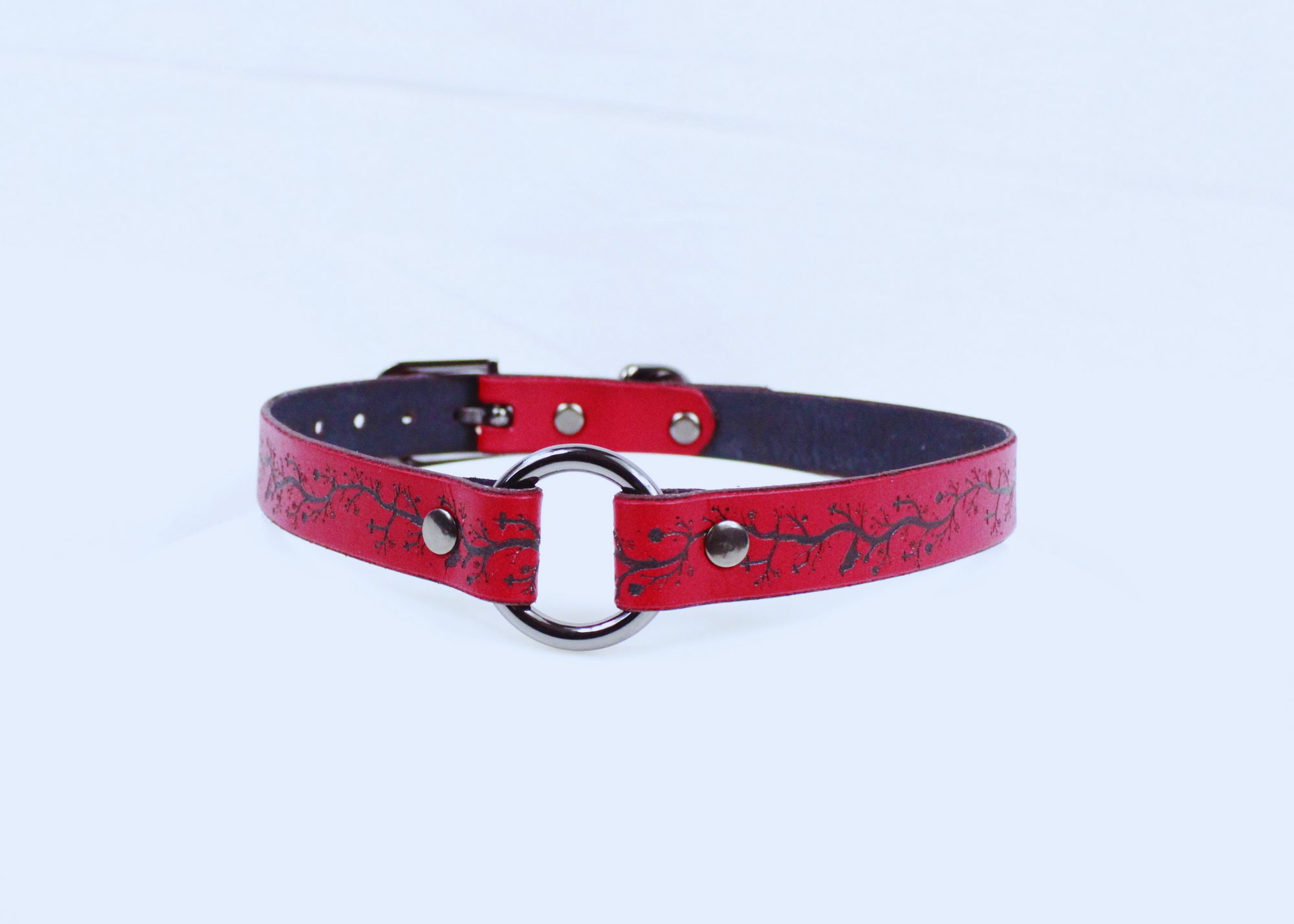 A red leather choker collar with a black metal ring and buckle.