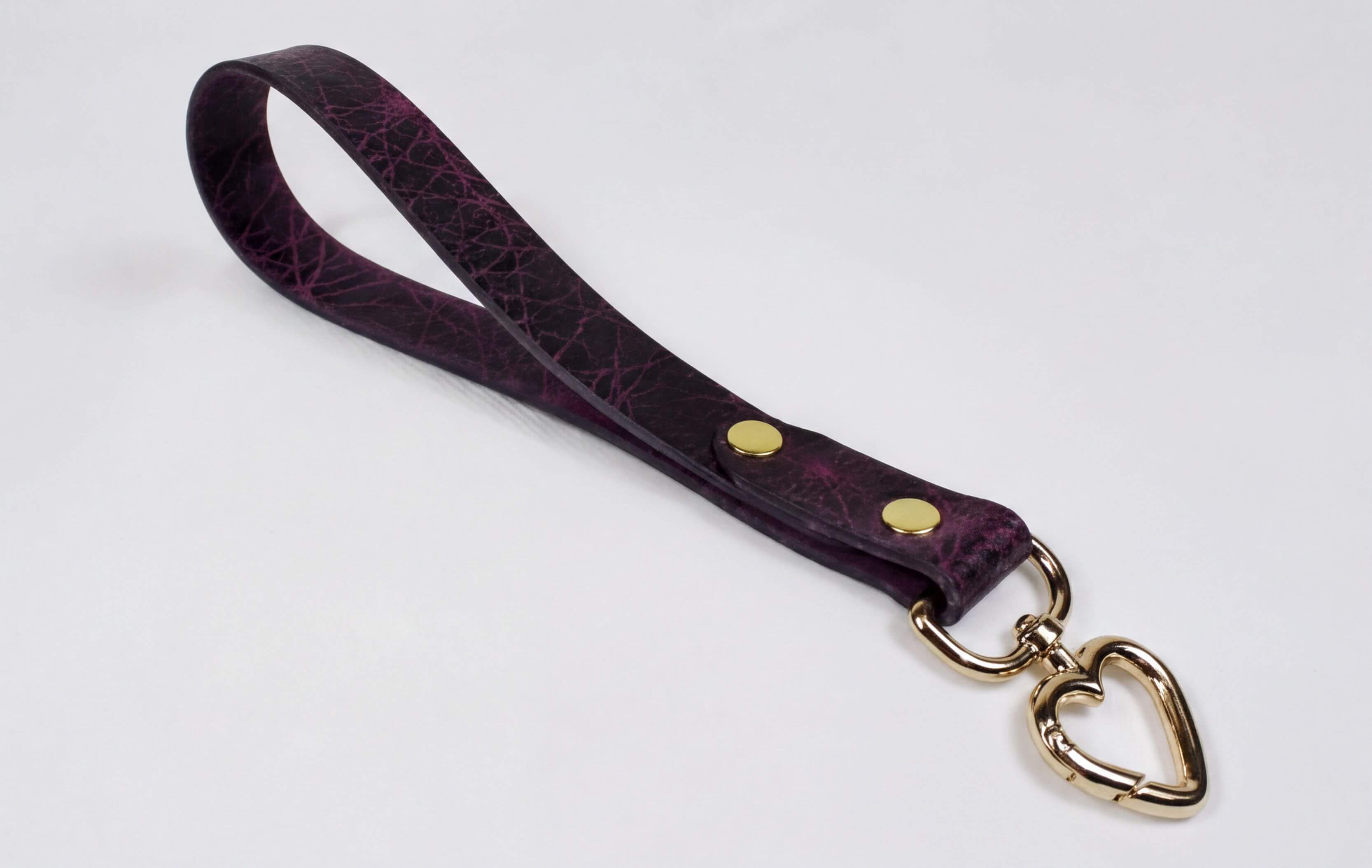 A purple leather strap with a heart-shaped metal clasp attached to it.