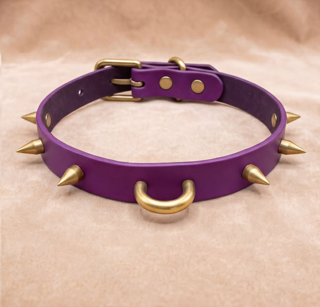 A purple leather collar with gold spikes protruding from it.
