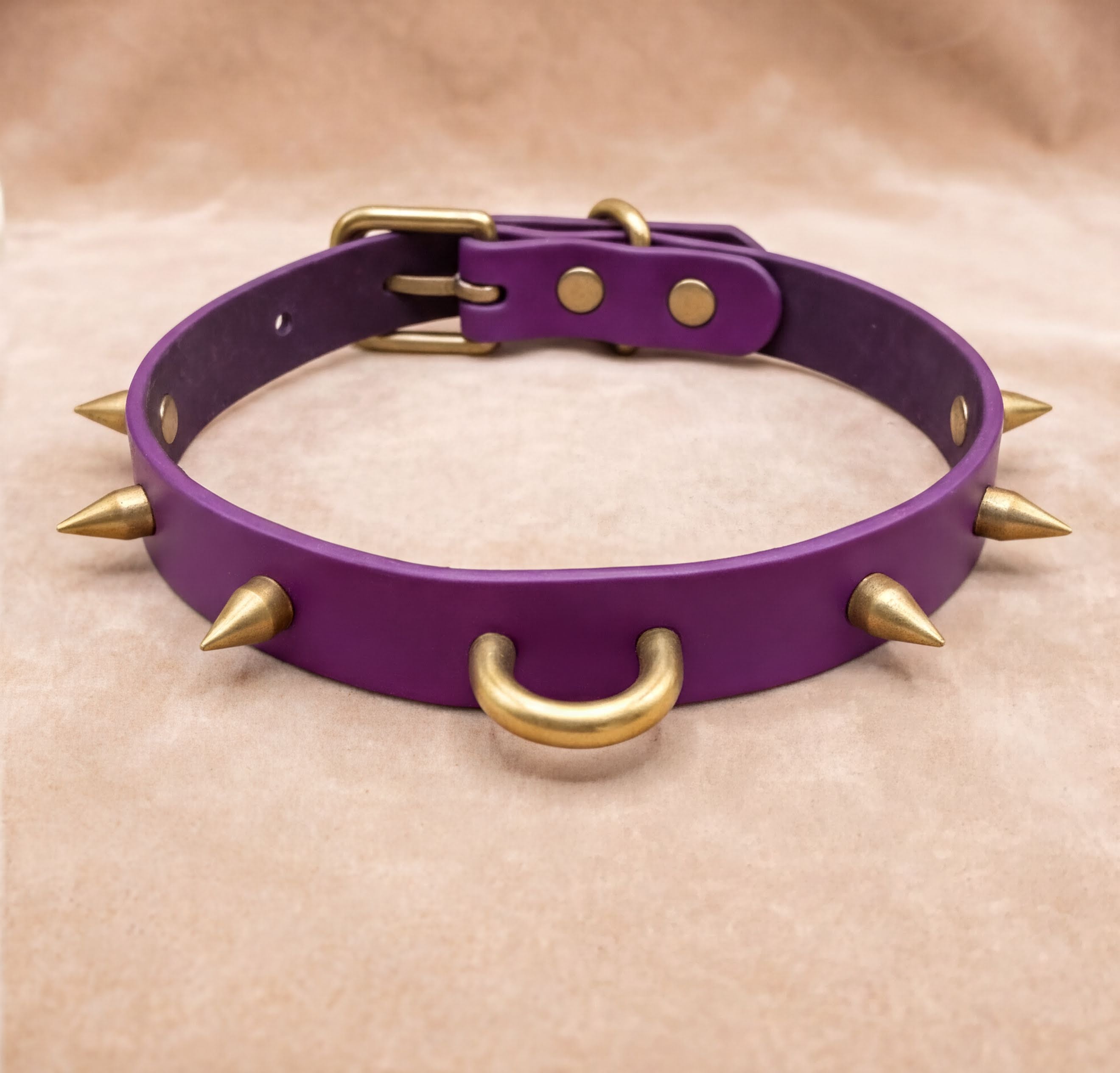 A purple leather collar with gold spikes protruding from it.