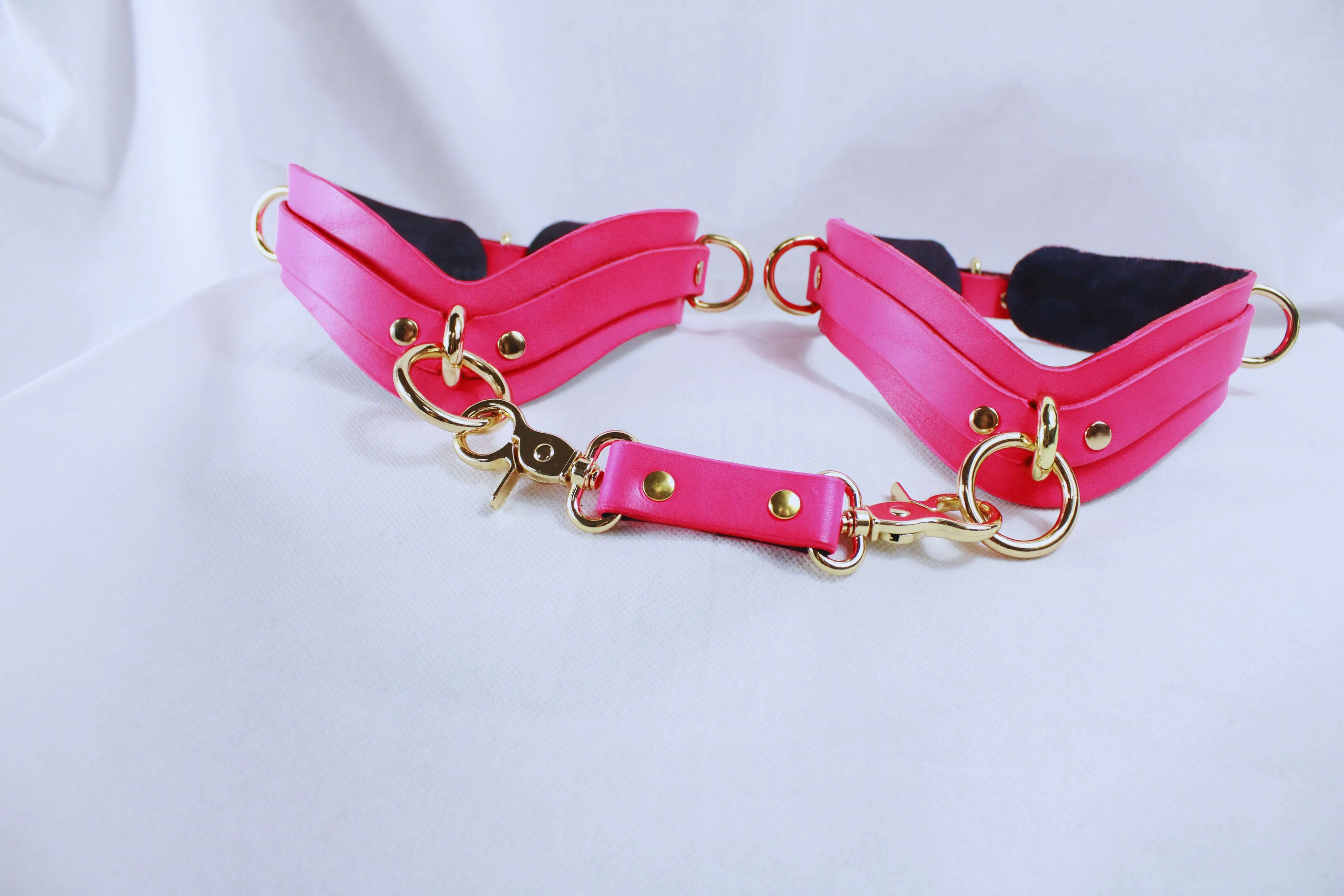Pink bondage gear collar and cuffs set with gold hardware for BDSM and submissive play.