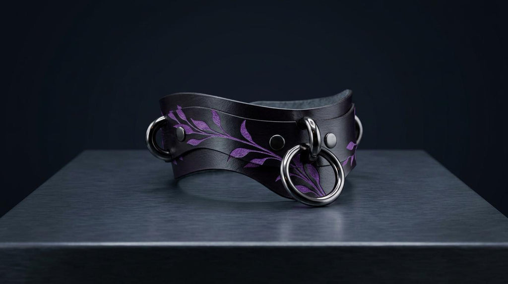 A black leather choker necklace with purple leaf designs and metal rings is displayed on a dark surface.