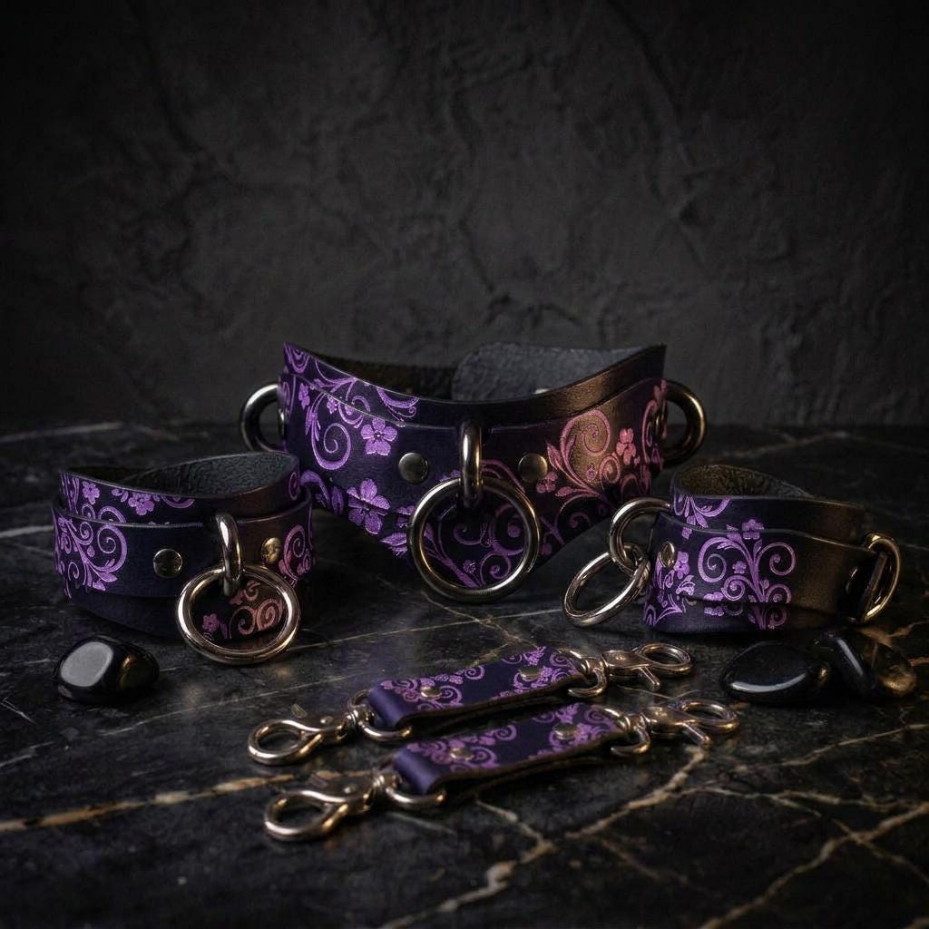 A set of purple and black leather straps with floral patterns, arranged on a dark surface.