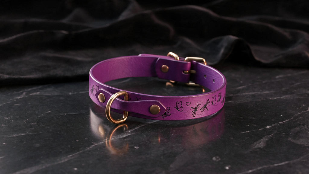 A purple leather collar with a gold-colored buckle and a small butterfly design is displayed on a black marble surface.