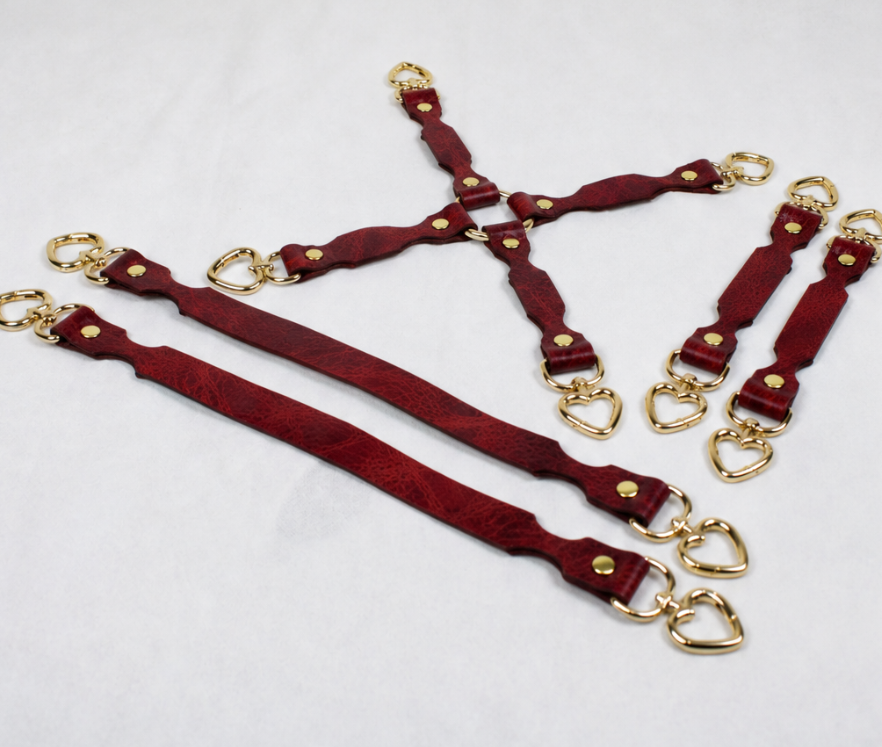 a collection of red leather straps with gold-colored heart-shaped buckles, arranged in various orientations on a white background.
