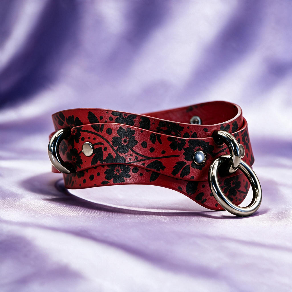 A red leather choker necklace with a floral pattern and metal rings on the ends, resting on a purple background.