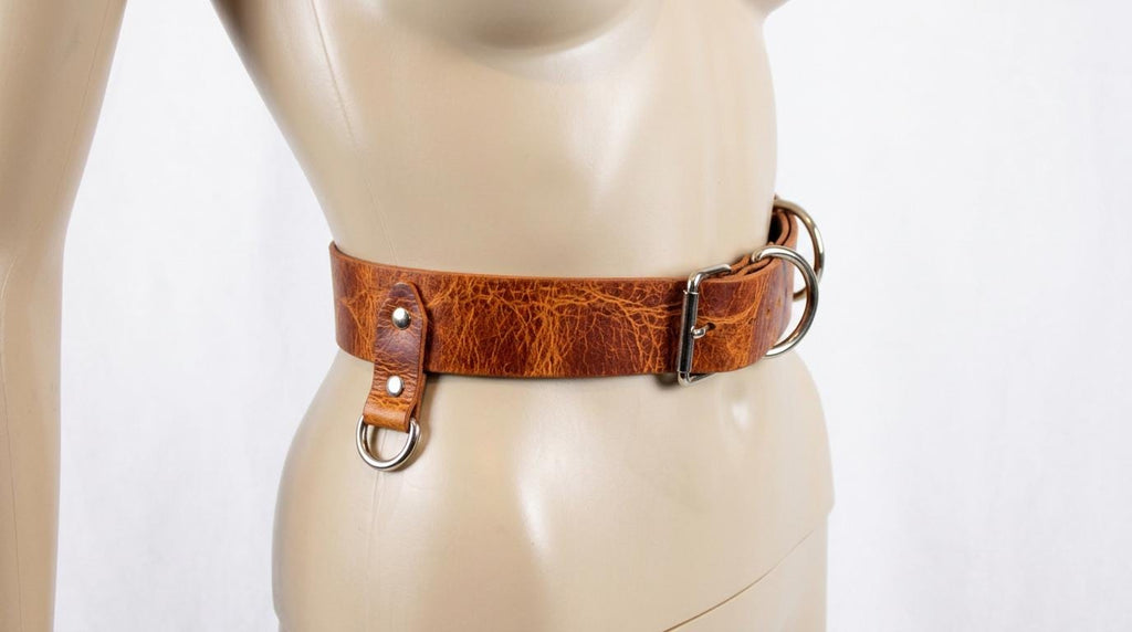 A mannequin wearing a brown leather belt with metal buckles.