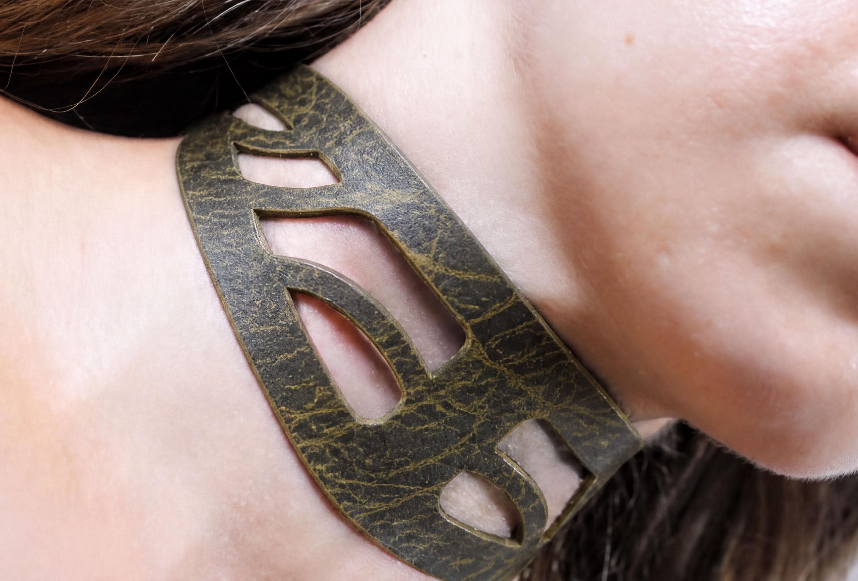 A close-up view of a person's neck and chin area, featuring a unique, textured leather necklace or choker.