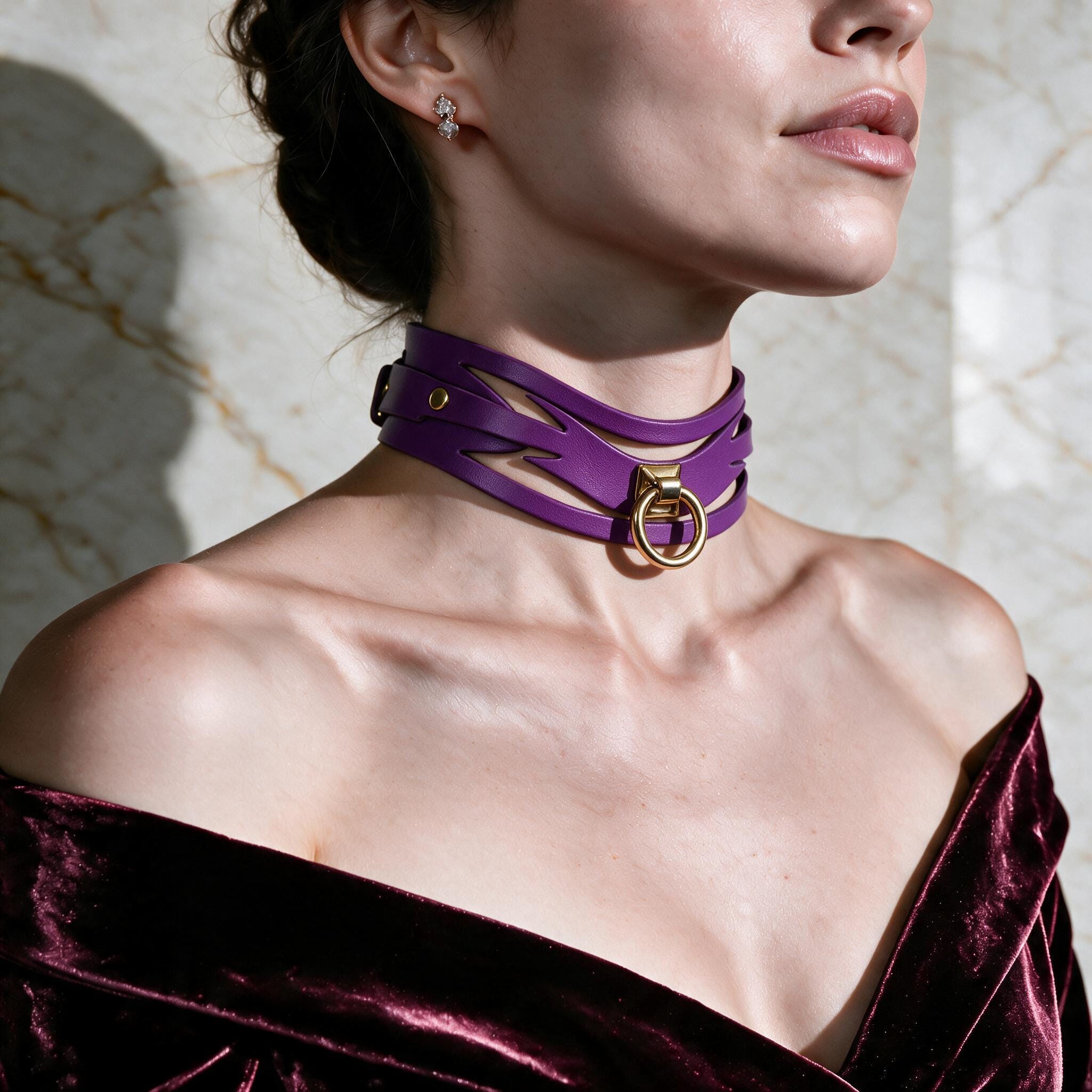 A woman wearing a purple choker necklace with a gold buckle, posing against a marble background.