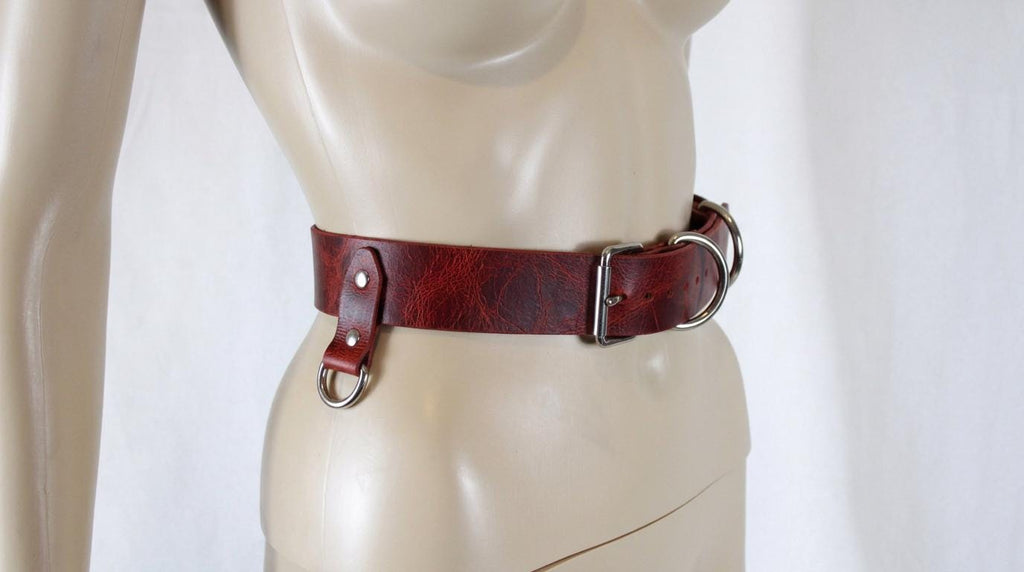 A mannequin wearing a red leather belt with a metal buckle.
