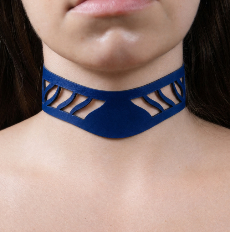 A close-up of a person's neck and chest area wearing a blue choker necklace with a unique cutout design.