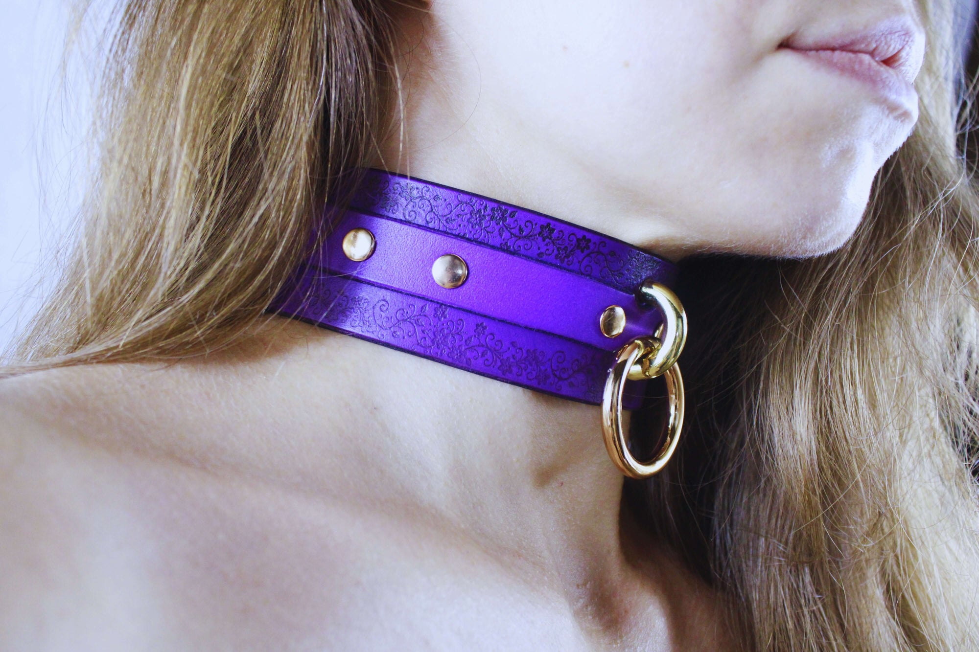 Floral Pattern Submissive Collar displayed on a model, featuring purple leather and gold accents for a stylish look.