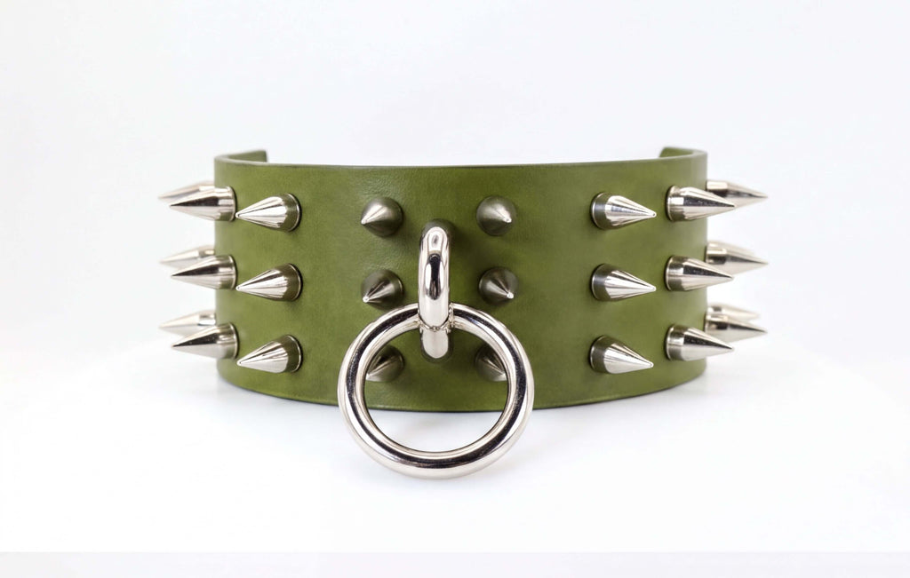 A green leather choker necklace with silver spikes protruding from it.