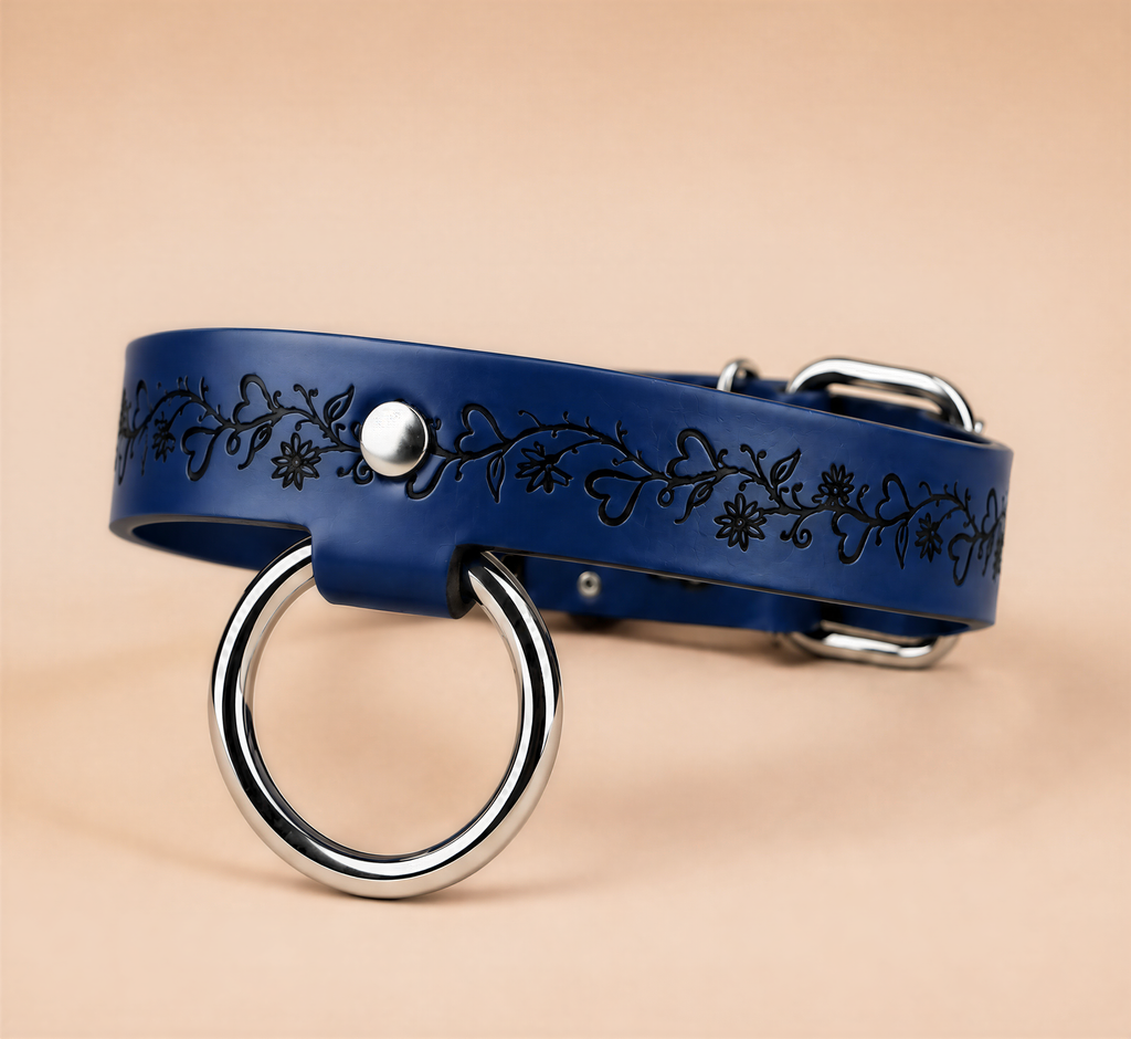 A blue leather collar with a metal ring and floral designs on the band.