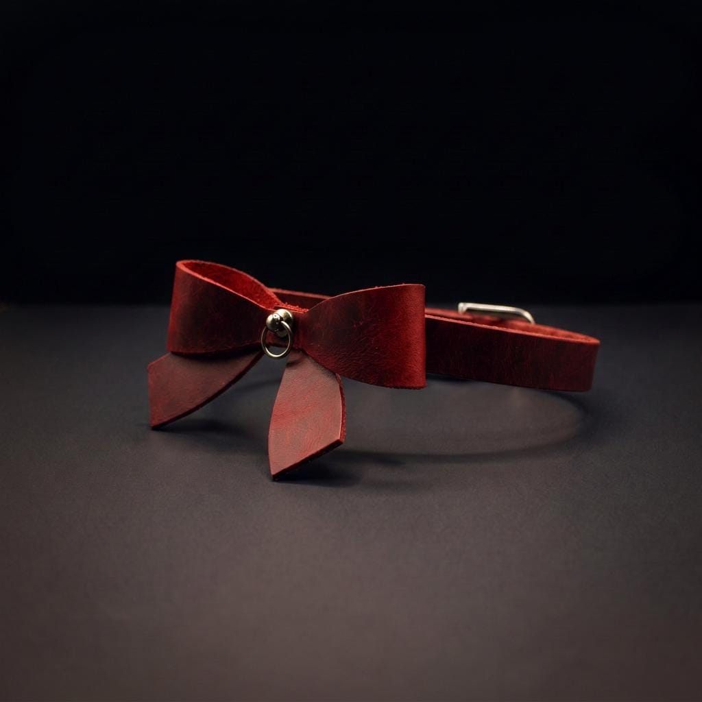 A red leather bow tie with a metal clasp is displayed against a dark background.