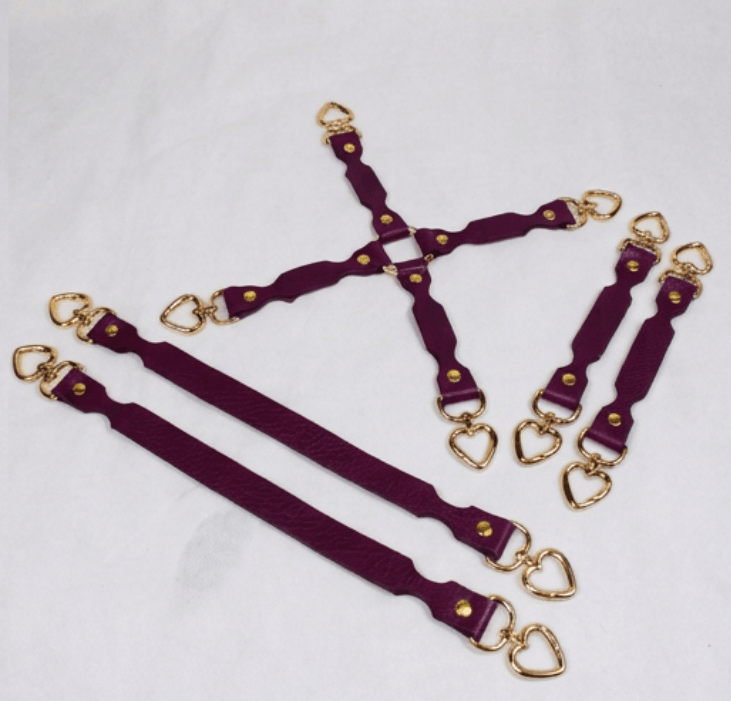 A set of purple leather straps with gold heart-shaped buckles, arranged in various orientations on a white background.