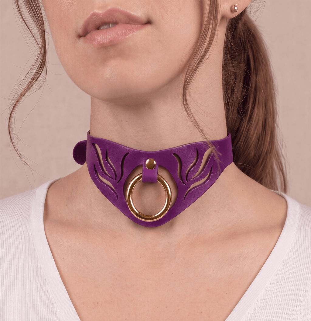 A close-up of a woman's neck and chest area, featuring a purple choker necklace with a gold ring and a floral design.