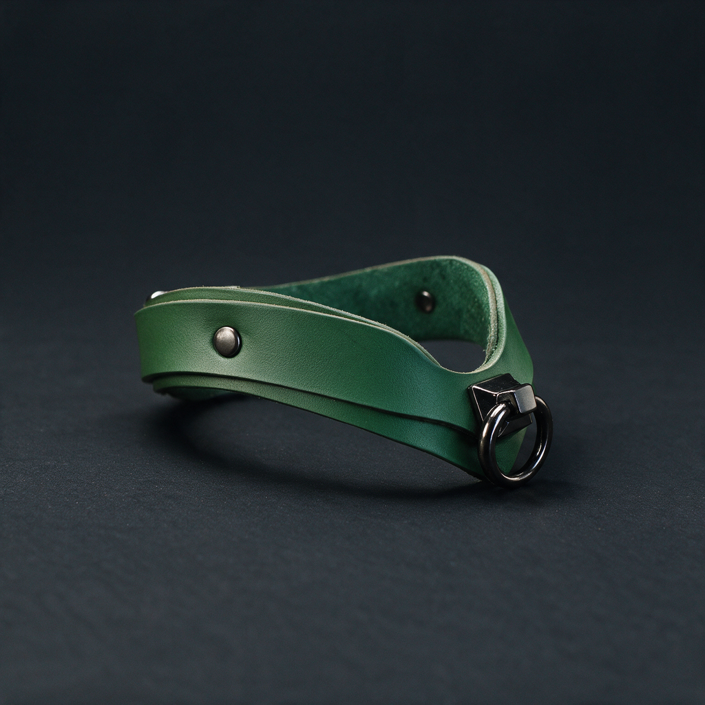 A green leather choker necklace with a metal clasp and buckle is shown against a dark background.