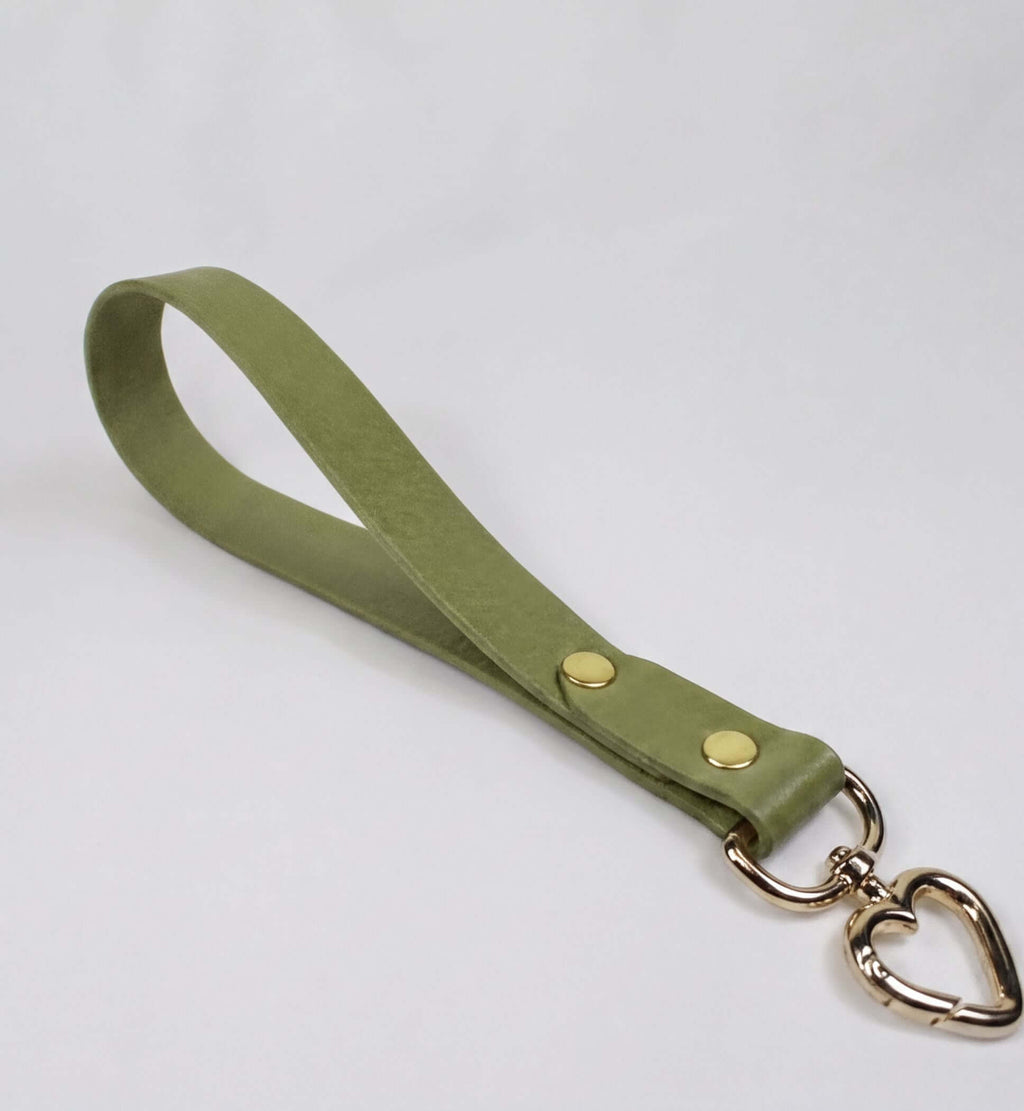 A green leather strap with a heart-shaped metal clasp attached to it.