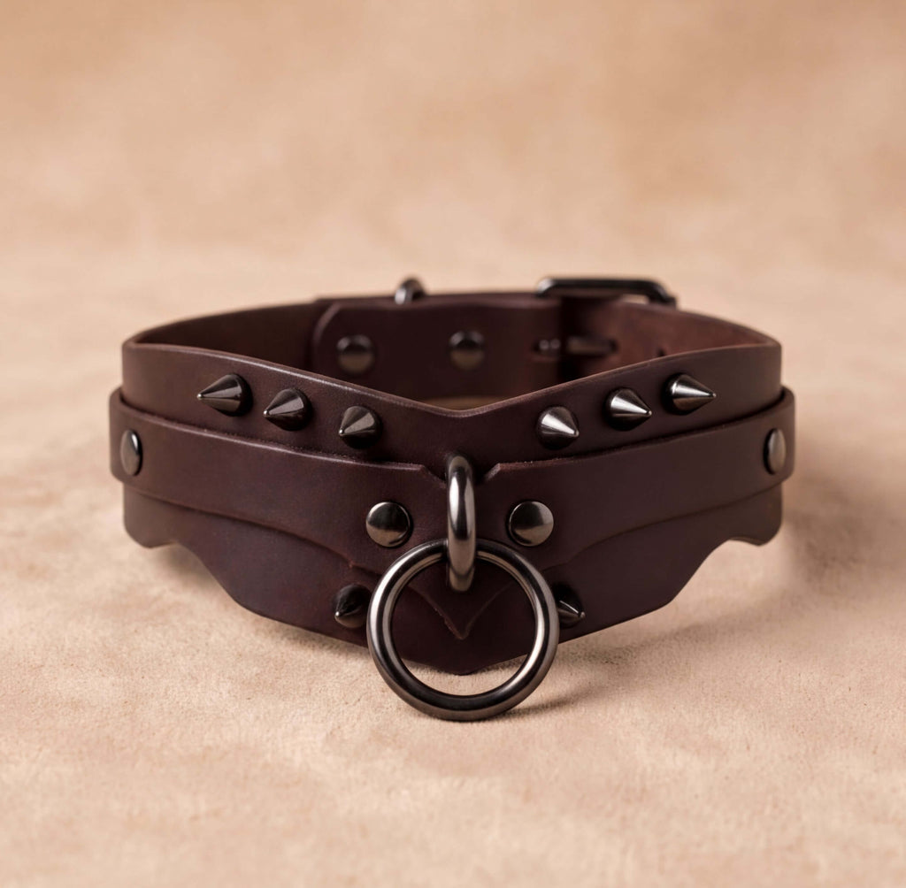 A brown leather choker necklace with spikes and a metal ring on the front.