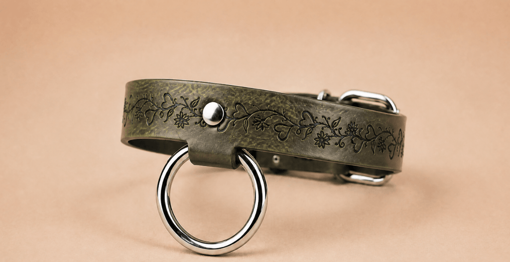 A green leather collar with a metal ring and a floral design on the band.