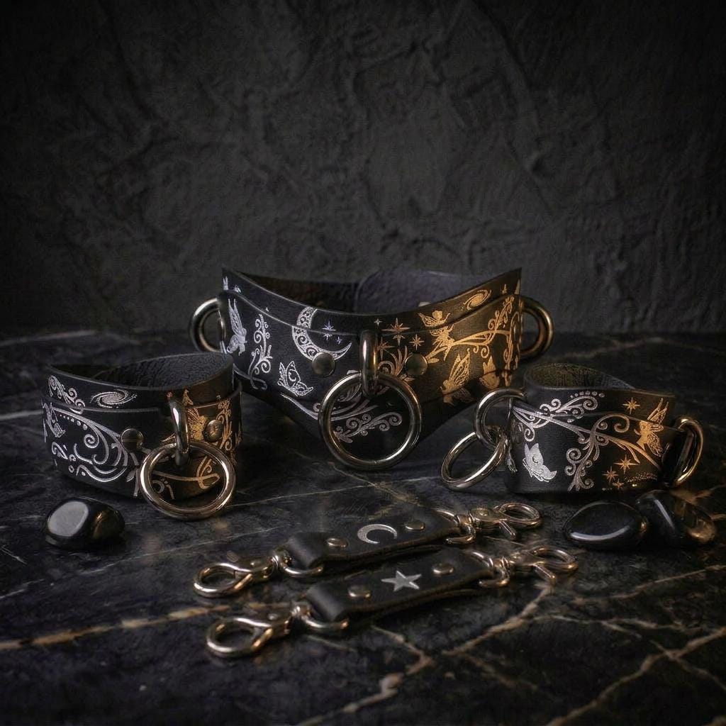 a collection of leather straps and buckles, including a pair of black straps with silver rings and a pair of black straps with silver buckles, all displayed on a dark surface.