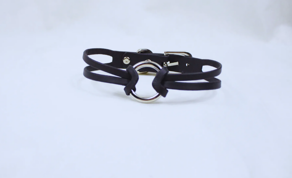 A black leather choker necklace with a silver circular clasp.