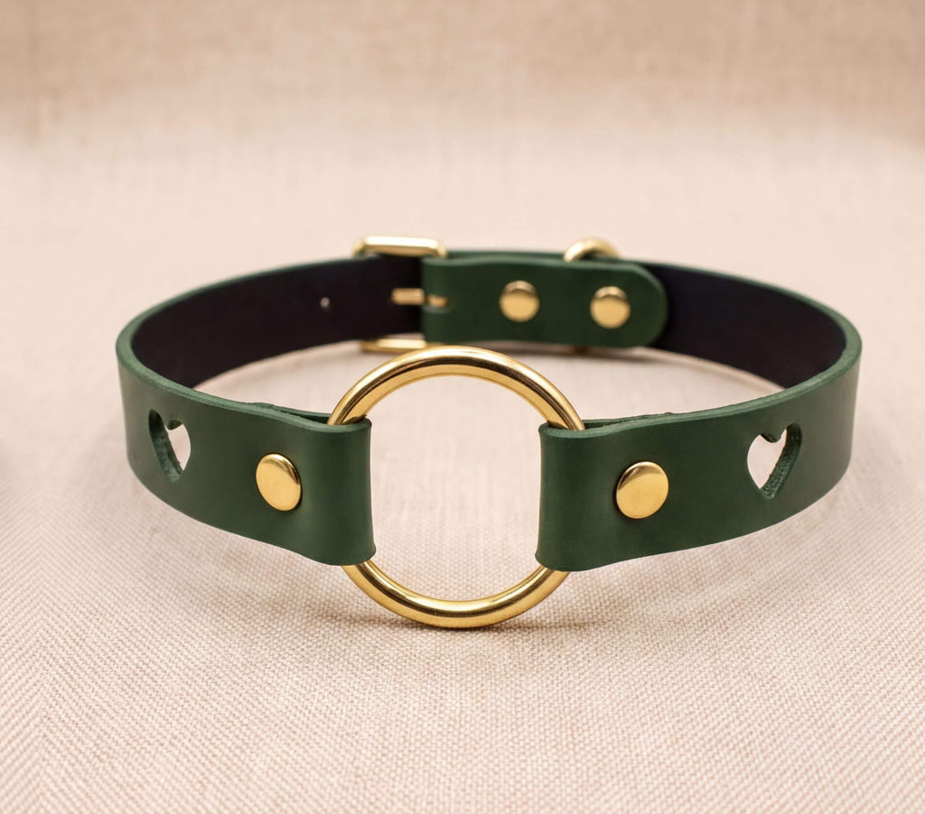 A green leather choker collar with a gold ring and two holes, one on each side.