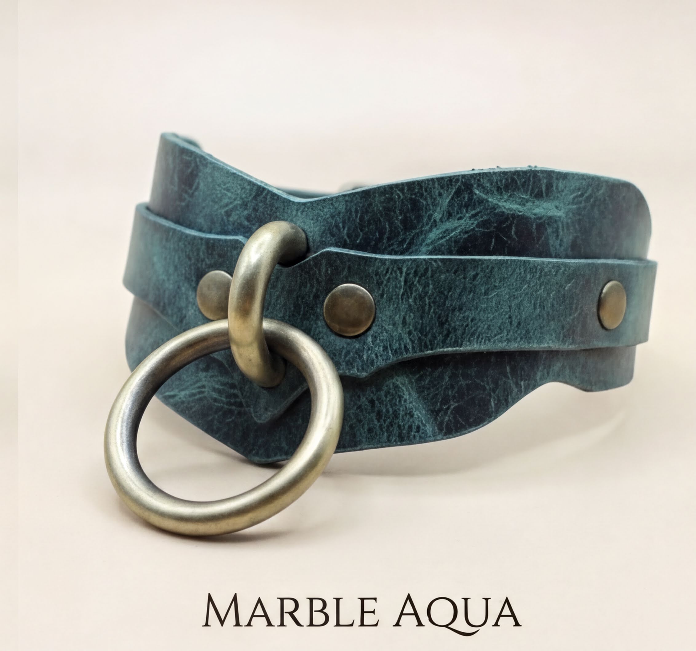 A close-up image of a green leather choker necklace with a metal ring and two metal studs on the front.