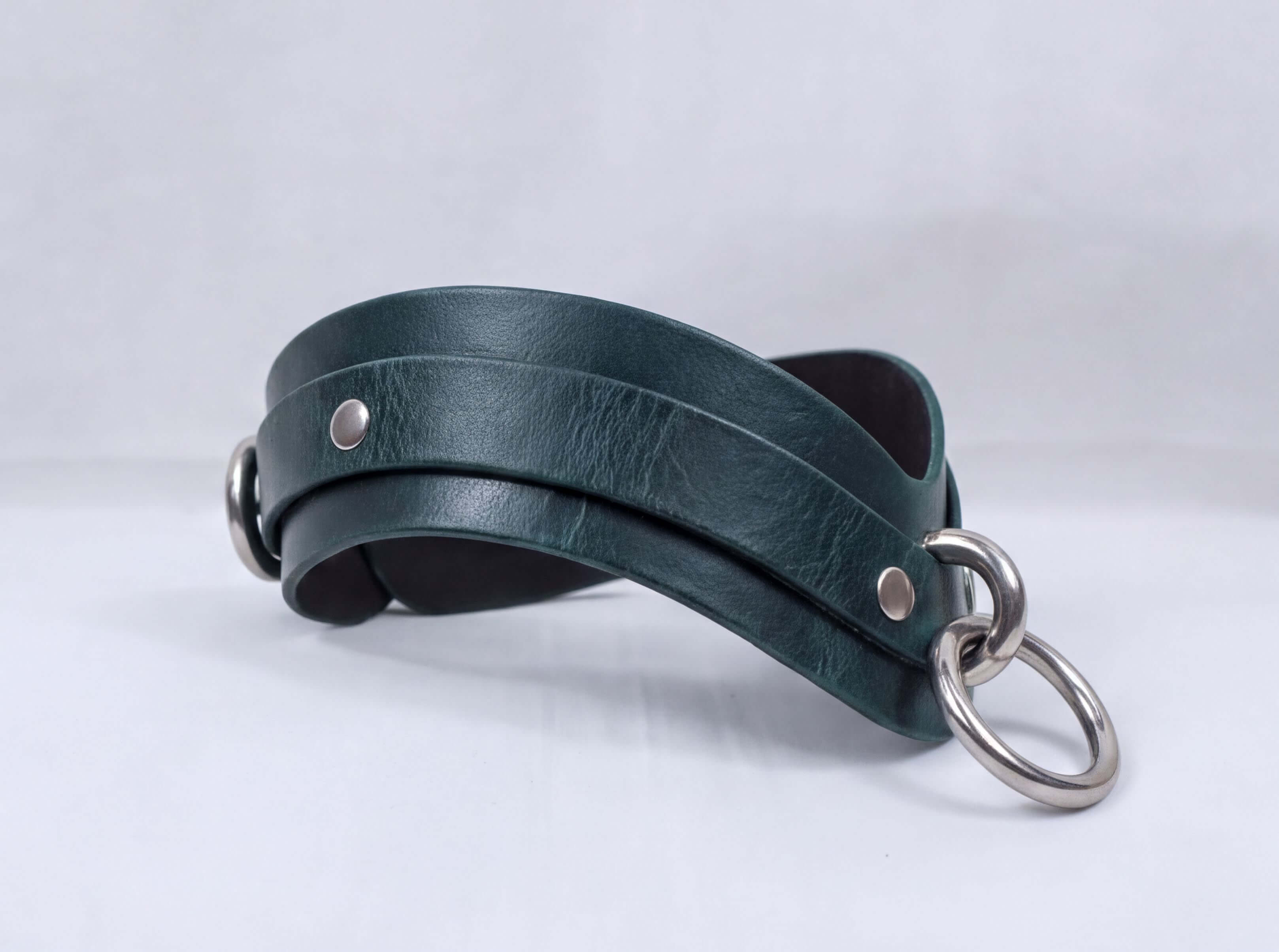 A dark green leather choker necklace with metal rings and a metal clasp.