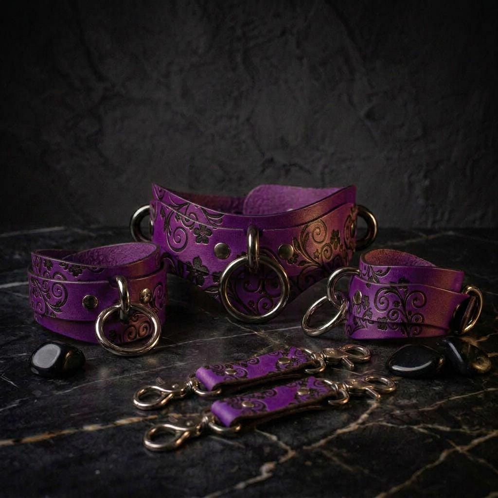 A collection of purple leather straps with metal rings and buckles, arranged on a dark surface.